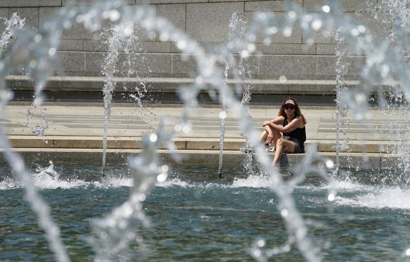 © Reuters. FILE PHOTO: A woman wearing a stars and stripes visor dips her foot into the cool fountain at the World War II Memorial on a possible record setting heat day in Washington, U.S., April 29, 2024. REUTERS/Kevin Lamarque/File Photo