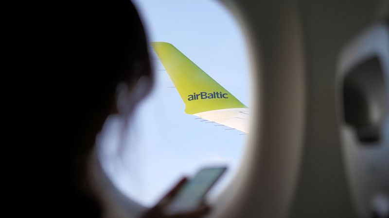 © Reuters. FILE PHOTO: Wing of an AirBaltic Airbus A220 is seen as a passenger holds a phone during a flight over Latvia, October 25, 2020. Picture taken October 25, 2020. REUTERS/Janis Laizans/File Photo